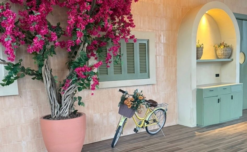 Pink bougainvillea beside a bicycle outside a pastel tiled building