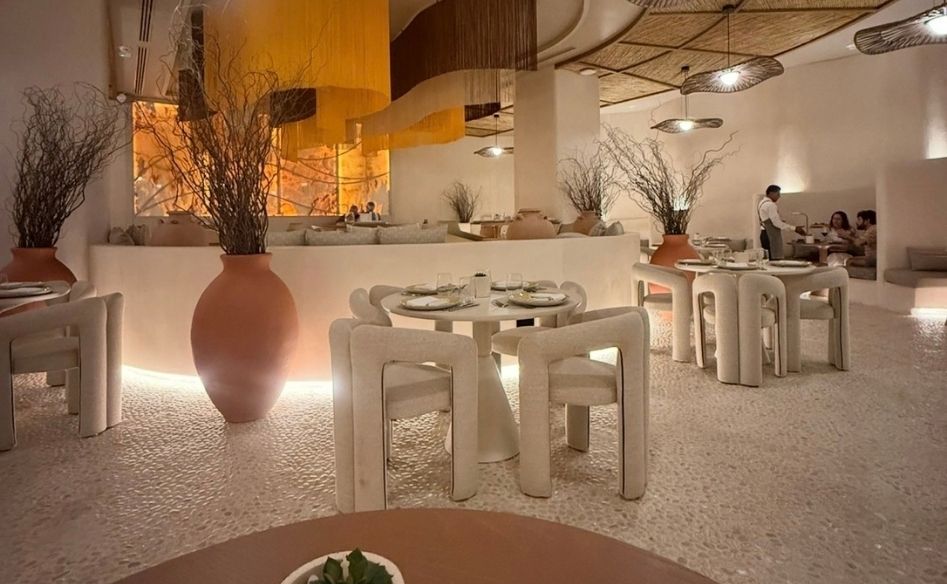 Restaurant interior with woven ceiling, pendant lights, white furniture, and clay vases